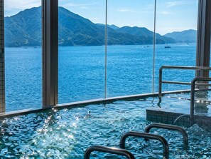 An indoor infinity pool with a view of a mountainous coastline.