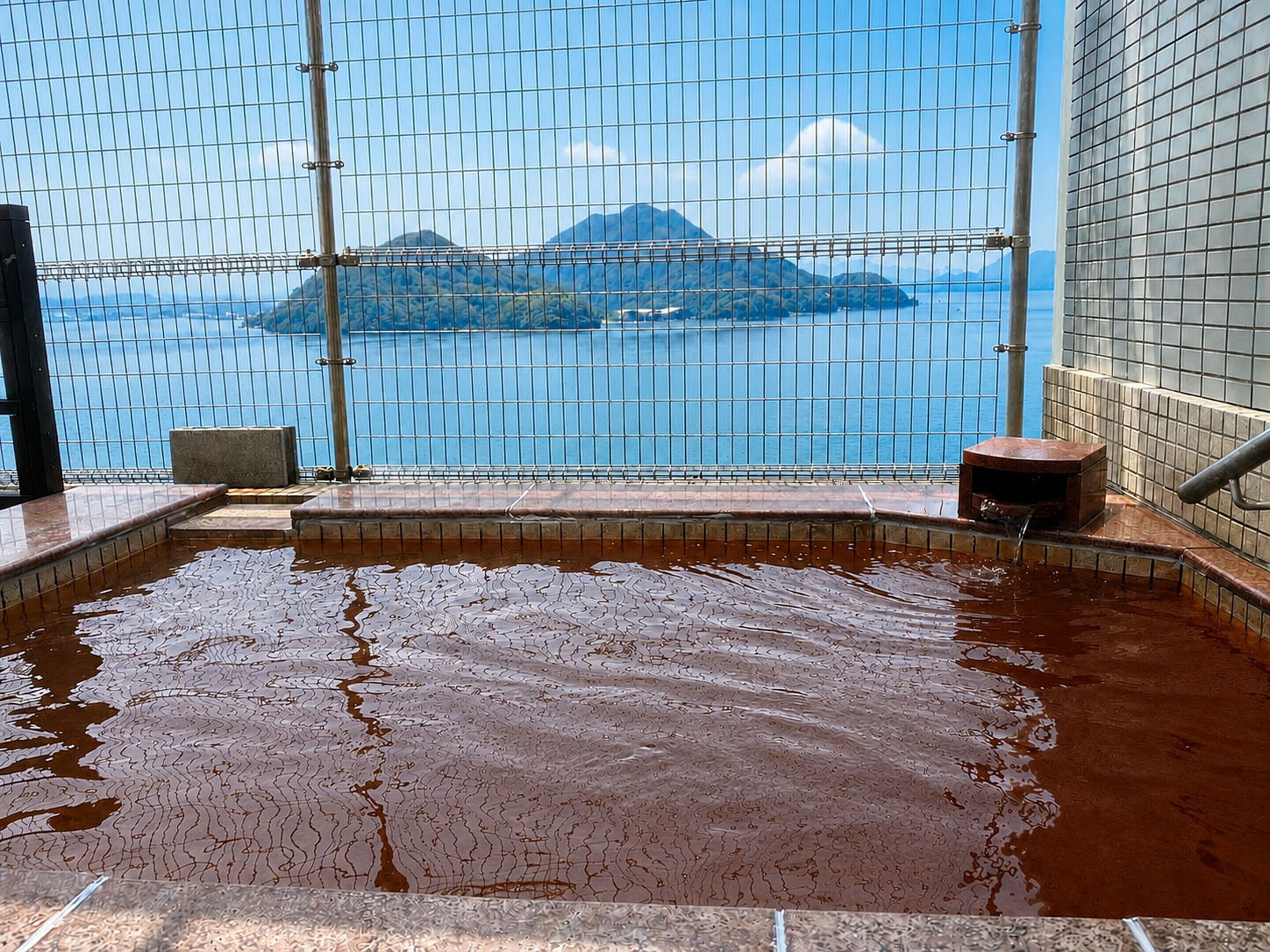 A hot spring area with a view of a mountainous landscape through a wire mesh.