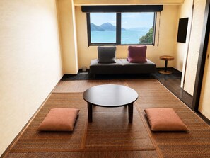 A room with a sofa, a small table, and a view of the sea. - Livemax Resort Mihara Sea Front (Mihara)