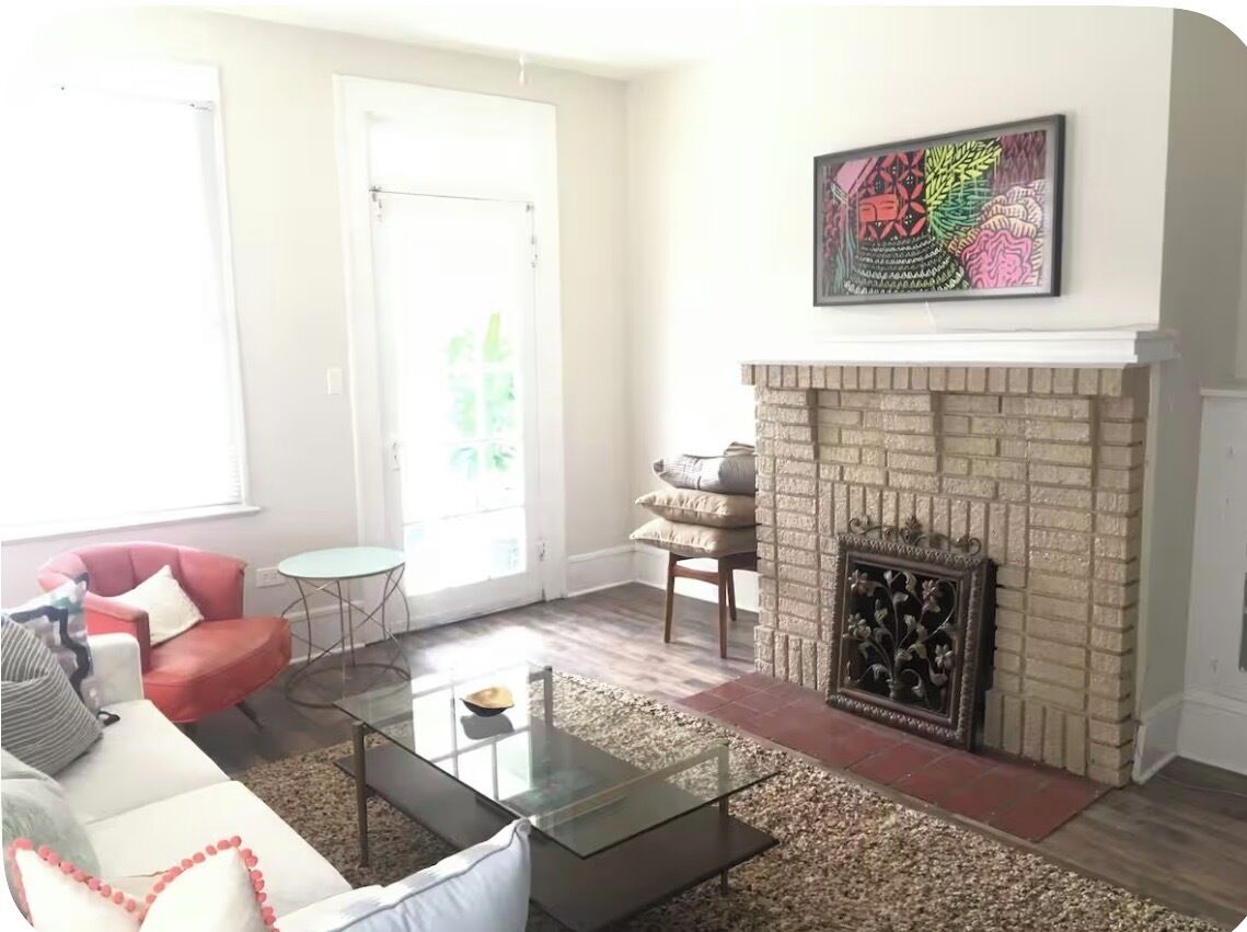 Un salon avec une cheminée, un canapé, une table basse et un tableau accroché au mur.