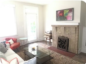 Ein Wohnzimmer mit Kamin, einer Couch, einem Couchtisch und einem Bild an der Wand.