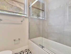 A bathroom with a glass-enclosed shower, a toilet, and a window with blinds. - Top floor of 1920’s duplex in the cool & eclectic 5-points Riverside area (Jacksonville)