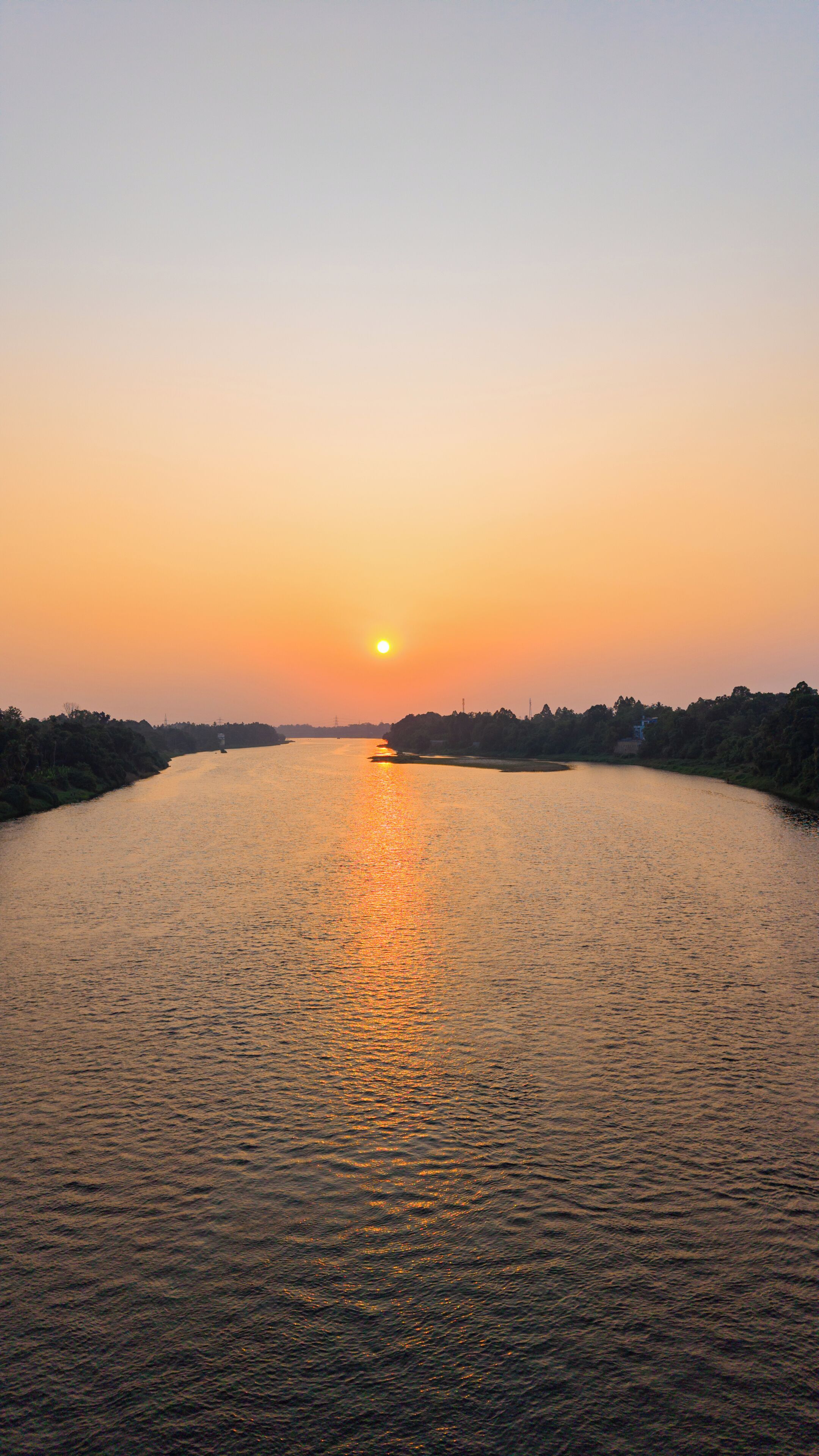 Um rio ao pôr do sol, com um barco ao longe.