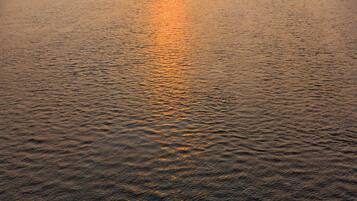 Um rio ao pôr do sol, com um barco ao longe.
