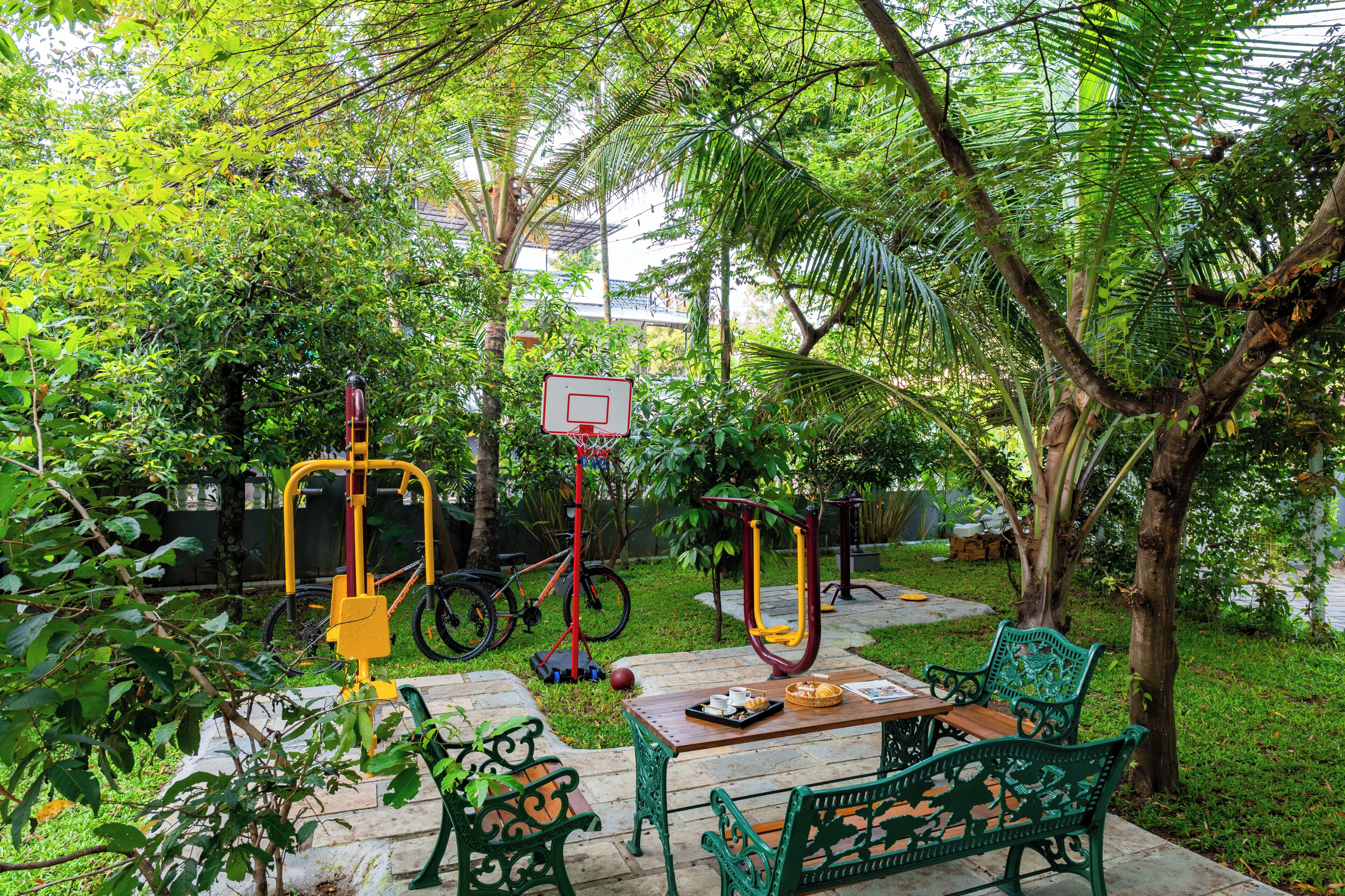 Un espacio al aire libre con equipo de ejercicio, una canasta de baloncesto y bancos verdes.