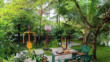 Un espacio al aire libre con equipo de ejercicio, una canasta de baloncesto y bancos verdes.
