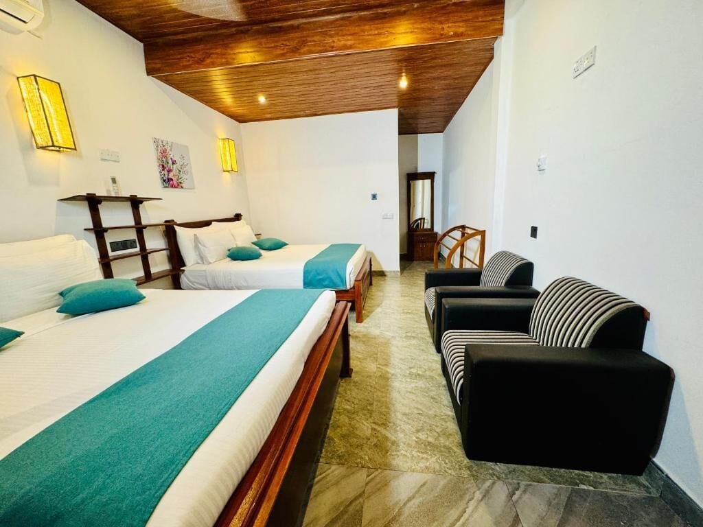A hotel room with two beds, a sofa, and a wooden ceiling.