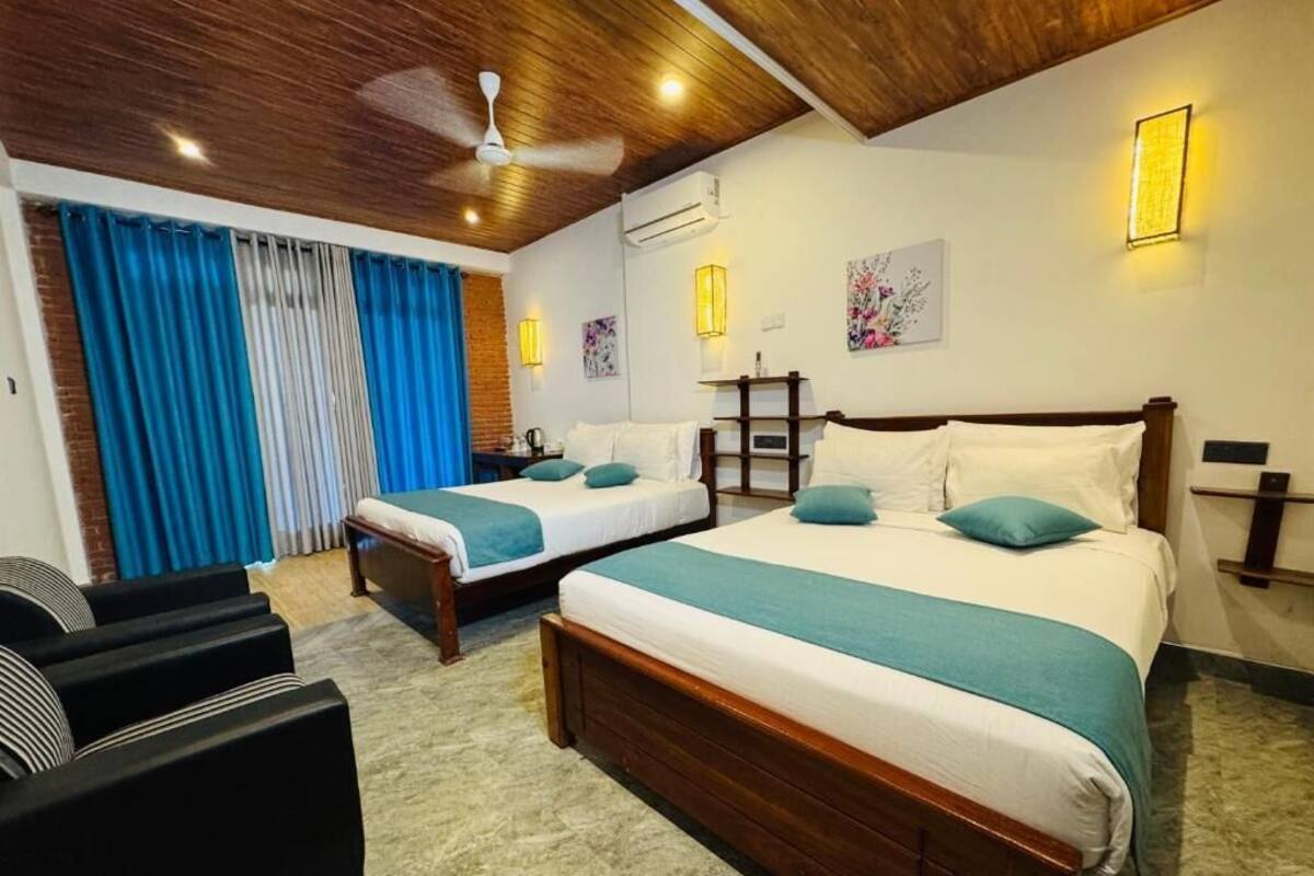 A hotel room with two beds, a ceiling fan, and a view of the outdoors.