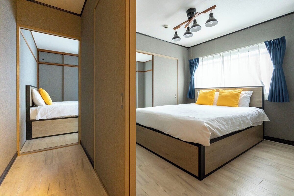 A bedroom with a bed, a wardrobe, a ceiling fan, and a window with curtains.
