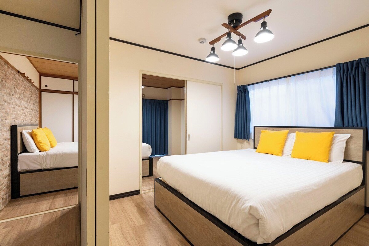 A hotel room with a large bed, a mirror, a ceiling fan, and a window with curtains.