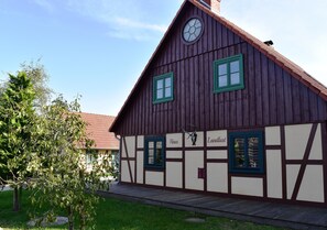A traditional half-timbered house with two windows, a chimney, and a clock. - Ferienhaus in Wendorf am Seenland (Kuhlen-Wendorf)