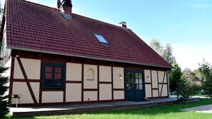 A traditional half-timbered house with a red-tiled roof, a small window, and a green door. - Ferienhaus in Wendorf am Seenland (Kuhlen-Wendorf)
