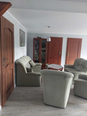 A living room with a sofa set, a wooden cabinet, and a hanging light fixture. - Apartment in Sopot Near Monte Cassino Street (Sopot)
