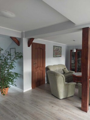 Un salon spacieux avec une porte en bois, un canapé, une petite table et une plante en pot.