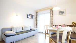 Ein modernes Wohnzimmer mit einer Couch, einem Esstisch, Stühlen und einem an der Wand befestigten Fernseher.