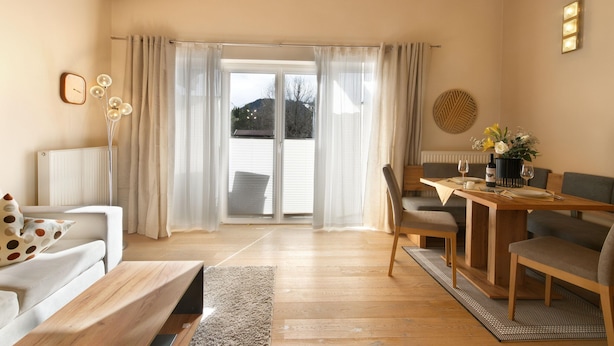 A living room with a sofa, a coffee table, a dining table with chairs, and a view through a glass door. - Tranquil Apartment in the Centre of Seefeld (Seefeld in Tirol)