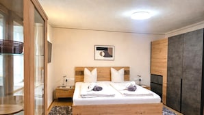 A modern bedroom with a wooden bed, two nightstands, a glass-enclosed wardrobe, and a marble-patterned rug. - Tranquil Apartment in the Centre of Seefeld (Seefeld in Tirol)