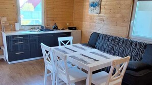 Puisesti sisustettu tila, jossa on ruokapöytä ja tuolit, sohva sekä keittiöalue.