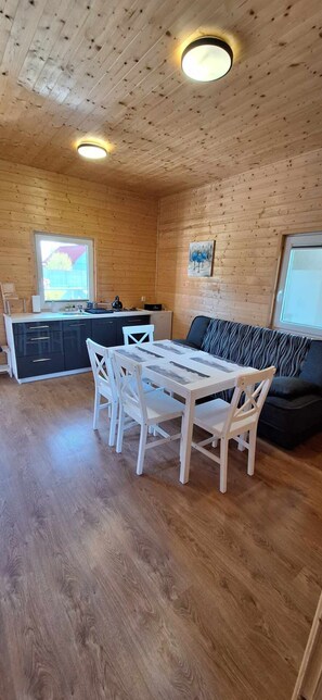 Un interior de madera con una mesa de comedor y sillas, un sofá y una zona de cocina.