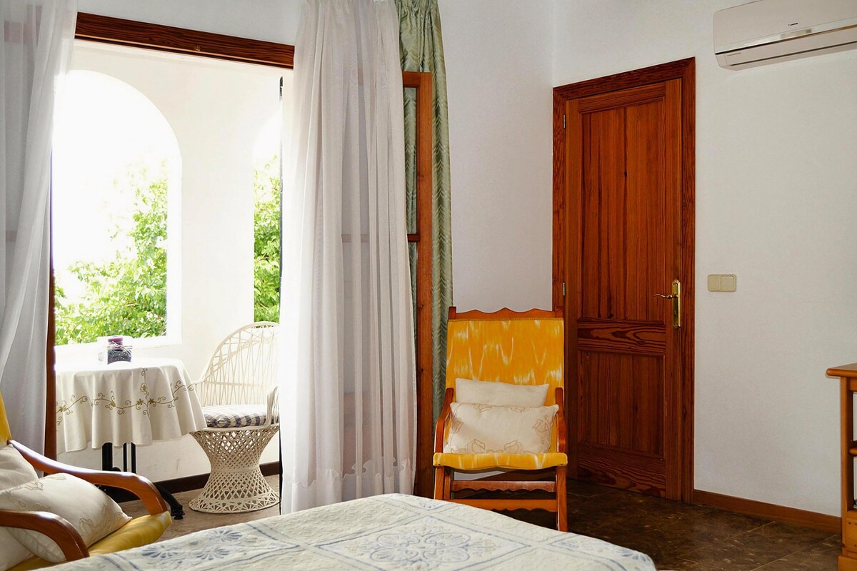 Ein Schlafzimmer mit einem Bett, einer Holztür, einem Stuhl und einem Tisch mit einer Tischdecke.