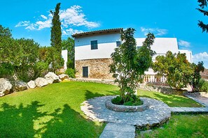 A white building with stone walls, a stone pathway, and a circular stone planter with a tree. - Finca in Muro With Panoramic Views (Santa Margalida)