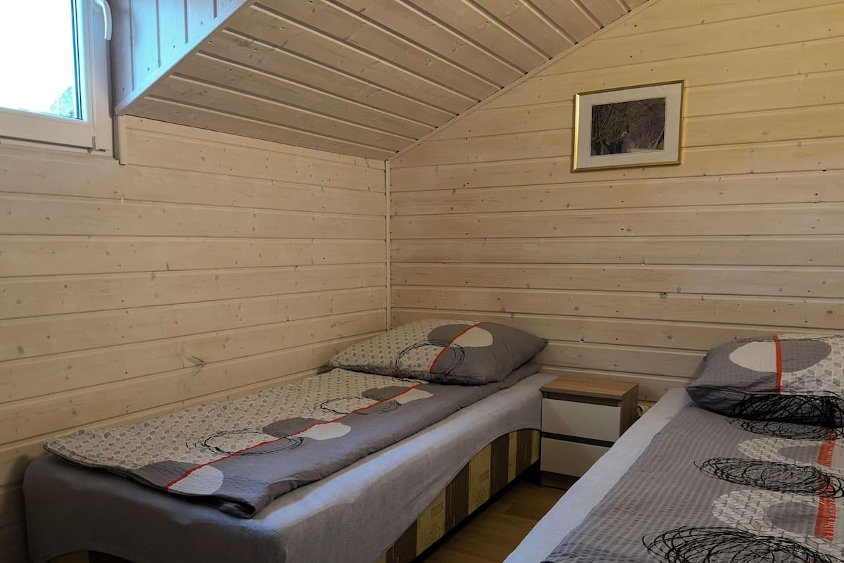 A small cabin with two single beds, a wooden ceiling, and a framed picture on the wall.