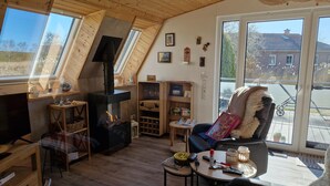 Accogliente camera mansardata con camino, arredamento in legno e ampie finestre che offrono vista sull'esterno.