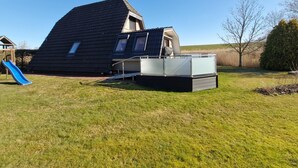 Una casa con tetto spiovente, uno scivolo blu e un piccolo spazio con veranda.