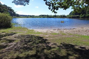 A lake with a sandy shore and a person in a kayak. - Holiday Home, Sauna, Jacuzzi, air Conditioning (gmina Sianów)