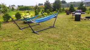 A hammock in a grassy outdoor area with a grill and potted plants. - Holiday Home, Sauna, Jacuzzi, air Conditioning (gmina Sianów)
