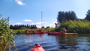 A calm river with kayaks, a clear sky, and greenery along the banks. - Holiday Home, Sauna, Jacuzzi, air Conditioning (gmina Sianów)