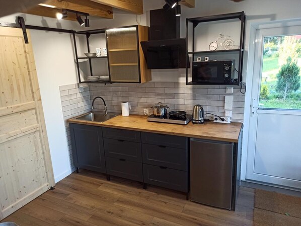 A modern kitchen with a wooden countertop, stainless steel appliances, and a view of greenery outside. - Holiday Home, Sauna, Jacuzzi, air Conditioning (gmina Sianów)