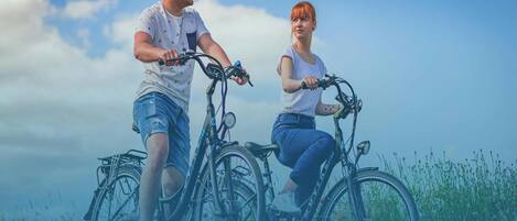 Two people on bicycles in a field with a clear sky.