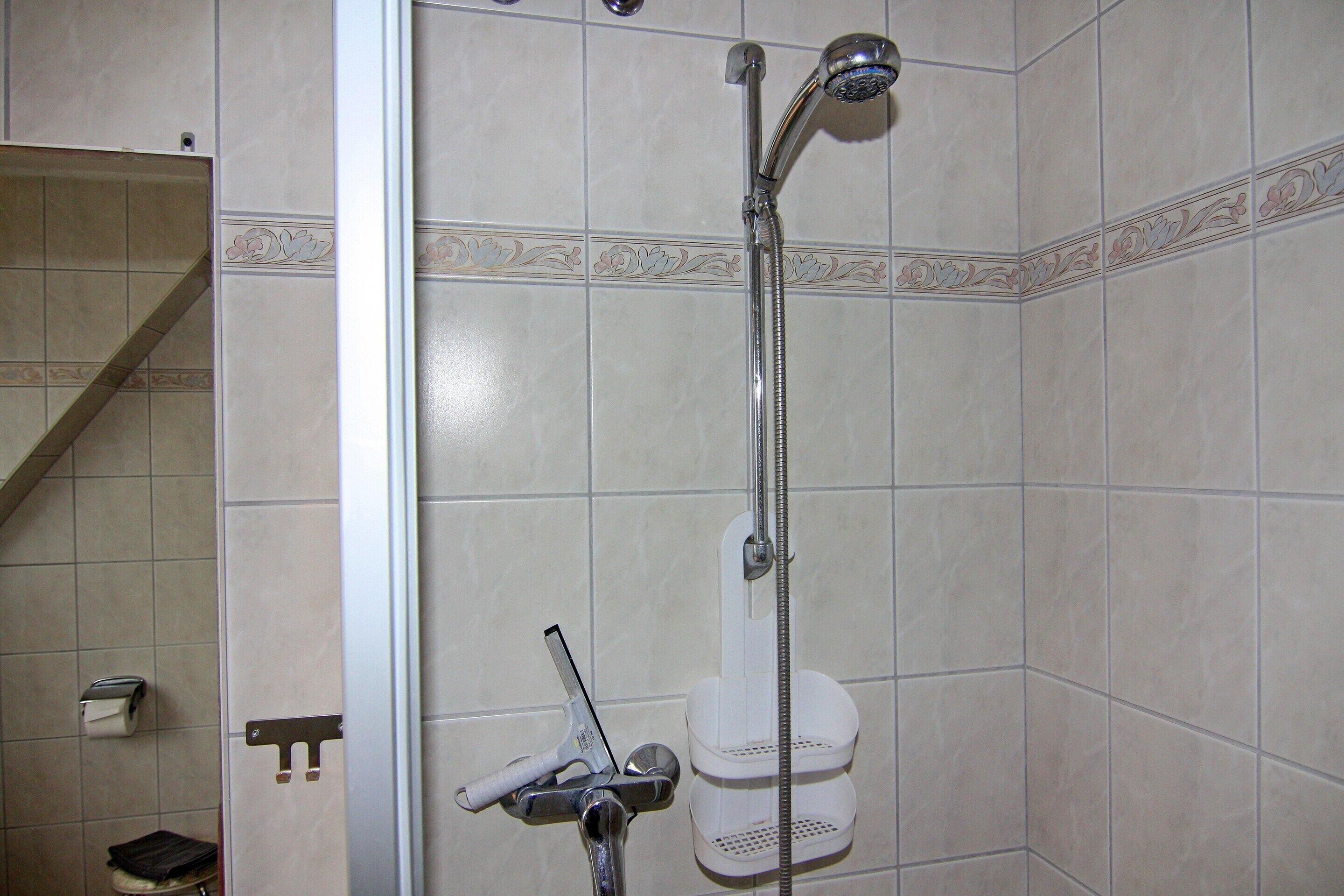 A bathroom with a shower, toilet, and a towel rack.