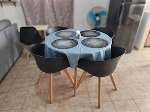A dining area with a round table, four black chairs, and a blue tablecloth.