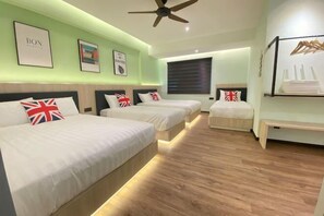 Ein Hotelzimmer mit drei Betten, einem Deckenventilator und einem großen Fenster.