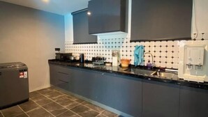 A modern kitchen with dark cabinets, a tiled backsplash, and a built-in oven. - 4BR 16pax LYL Jaccuzi Private Pool House ipoh (Ipoh)