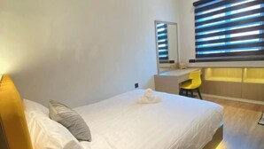 A hotel room with a bed, a desk, a chair, a mirror, and a window with blinds. - 4BR 16pax LYL Jaccuzi Private Pool House ipoh (Ipoh)