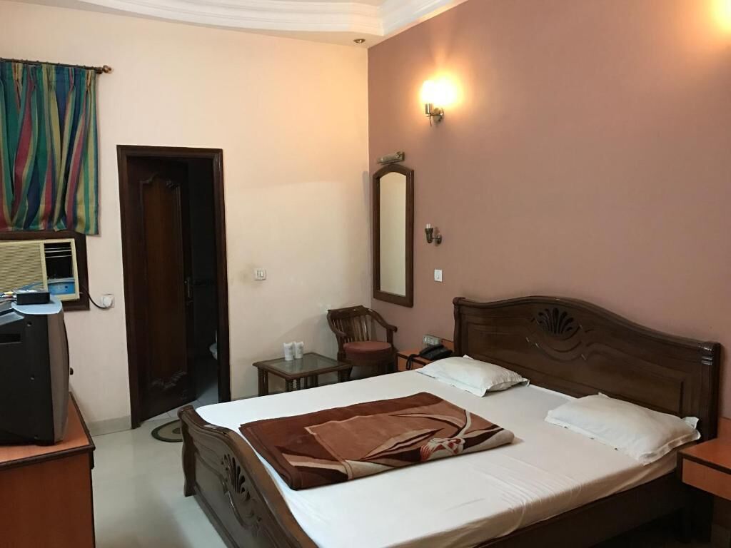 Ein Hotelzimmer mit Bett, Schreibtisch, Stuhl, Spiegel und Wandlampe.