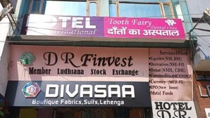 Un bâtiment orné de plusieurs enseignes, notamment « DR Finvest Member Ludhiana Stock Exchange », « DIVASAA Boutique Fabrics, Suits, Lehenga » et « Tooth Fairy Dental Clinic ».