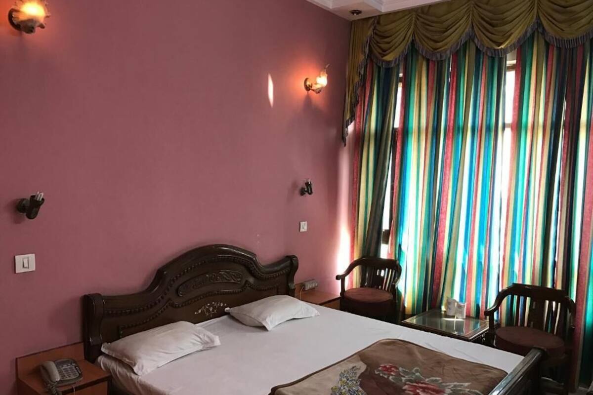 Una stanza con un letto, un comodino con il telefono, una sedia e un tavolo con una lampada.