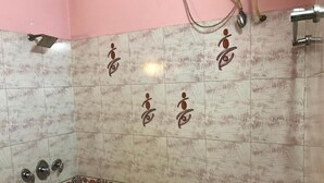 Une salle de bain carrelée avec un mur rose, un espace douche et une bordure décorative.