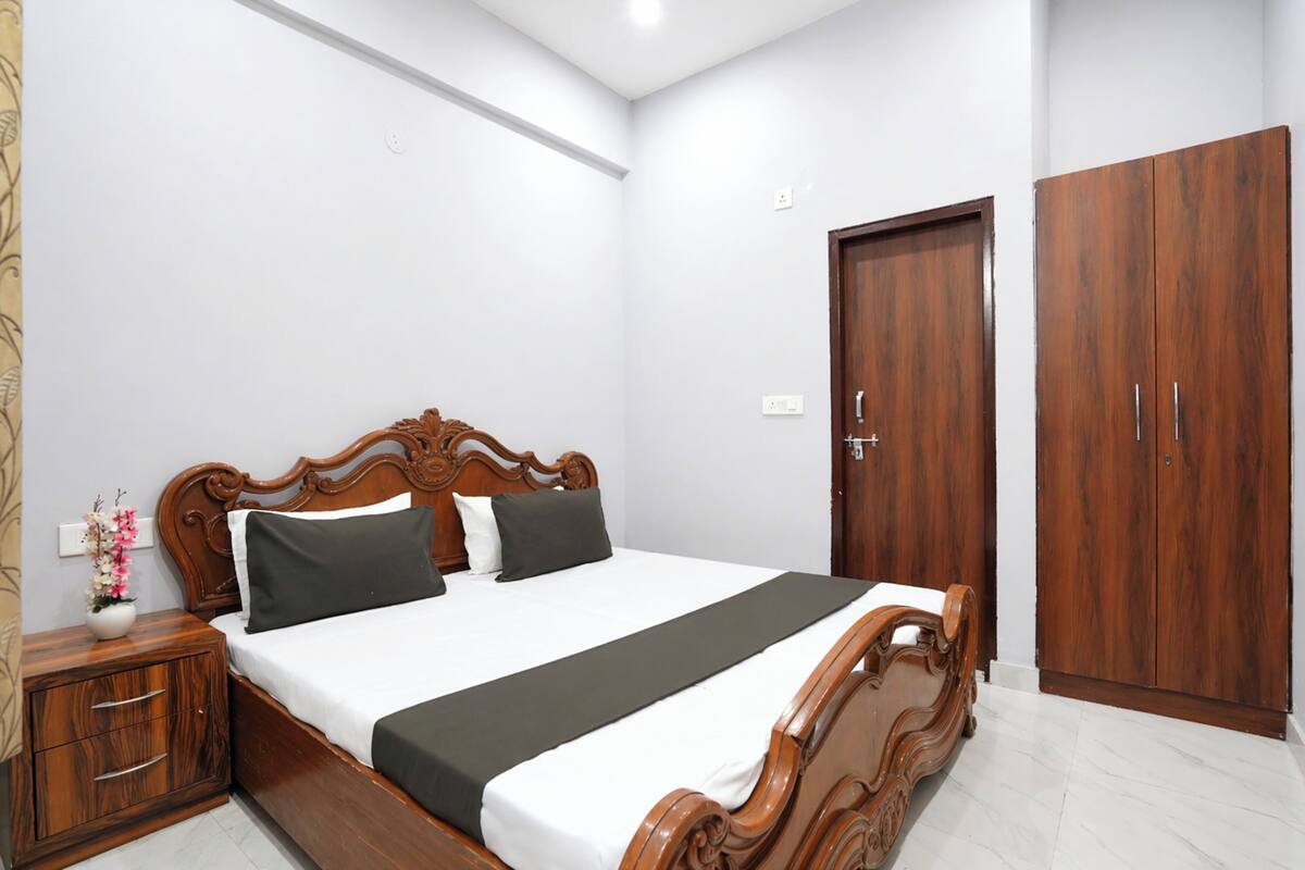 Quarto com cama de madeira, mesa de cabeceira, guarda-roupa e interruptor de luz na parede.