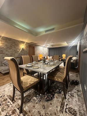 Un comedor con una mesa larga dispuesta para seis personas, rodeada de sillas tapizadas.
