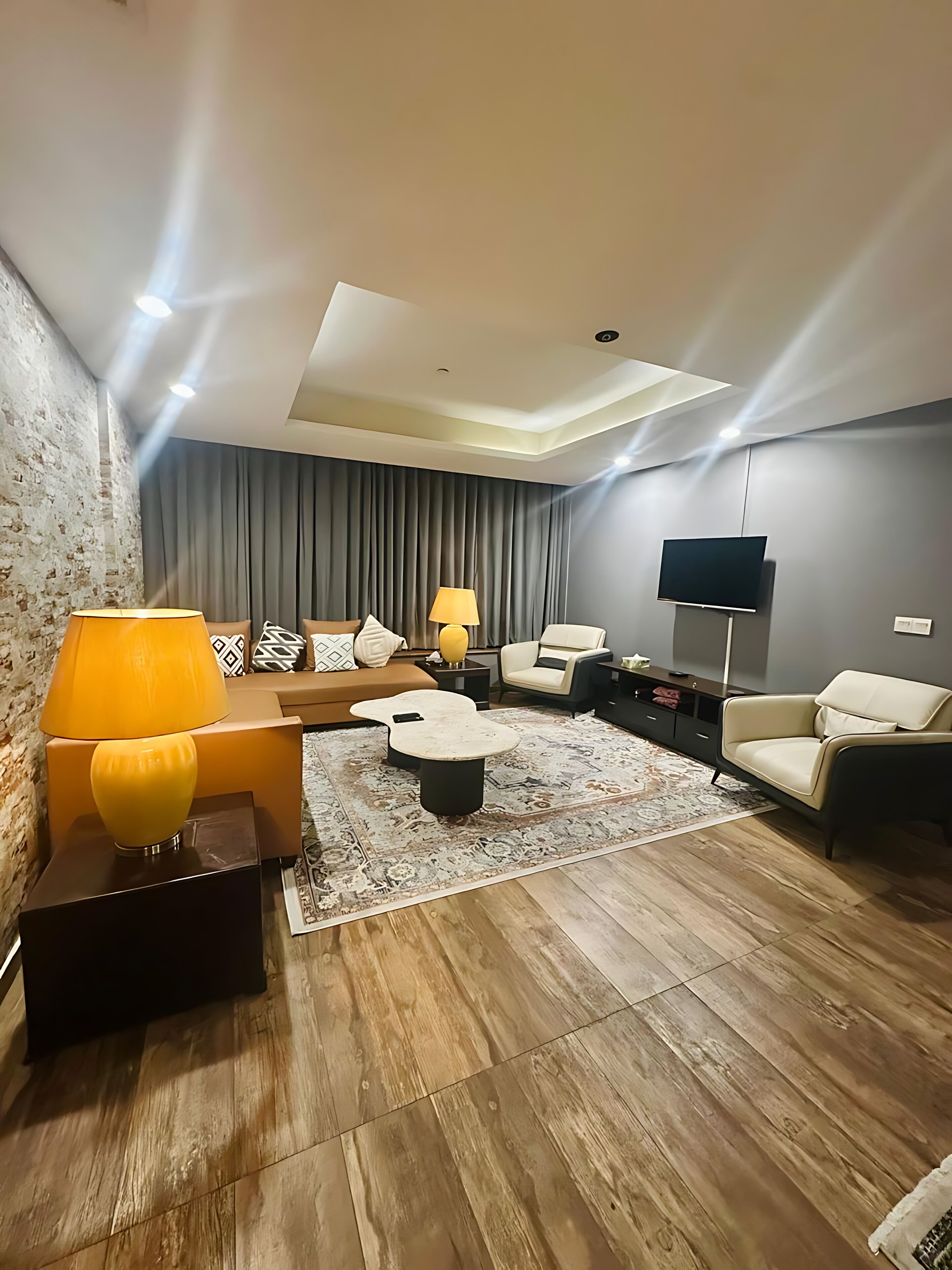 A modern living room with a sofa, armchairs, a coffee table, and a TV.