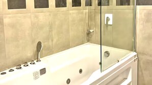 A modern bathroom with a glass-enclosed shower, a large bathtub, and a wall with square mirrors. - Centaurus Ultra Luxury Apartments (Islamabad)