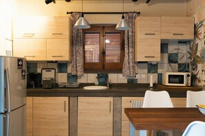 A kitchen with wooden cabinets, a microwave, a toaster, and a sink. - Paphos Traditional Holiday House (Mesa Chorio)