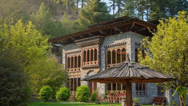 A stone building with a wooden roof, surrounded by greenery and trees. - Mountain Resort (Jakar)