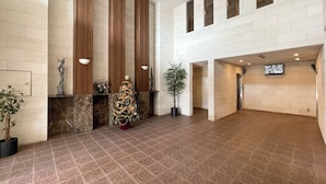 A spacious lobby with a Christmas tree, potted plants, and a statue on the wall. - CITYSPIRE Namba WEST (Osaka)