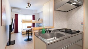 A compact kitchen with a sink, stove, and a small dining area with a table and chairs. - CITYSPIRE Namba WEST (Osaka)